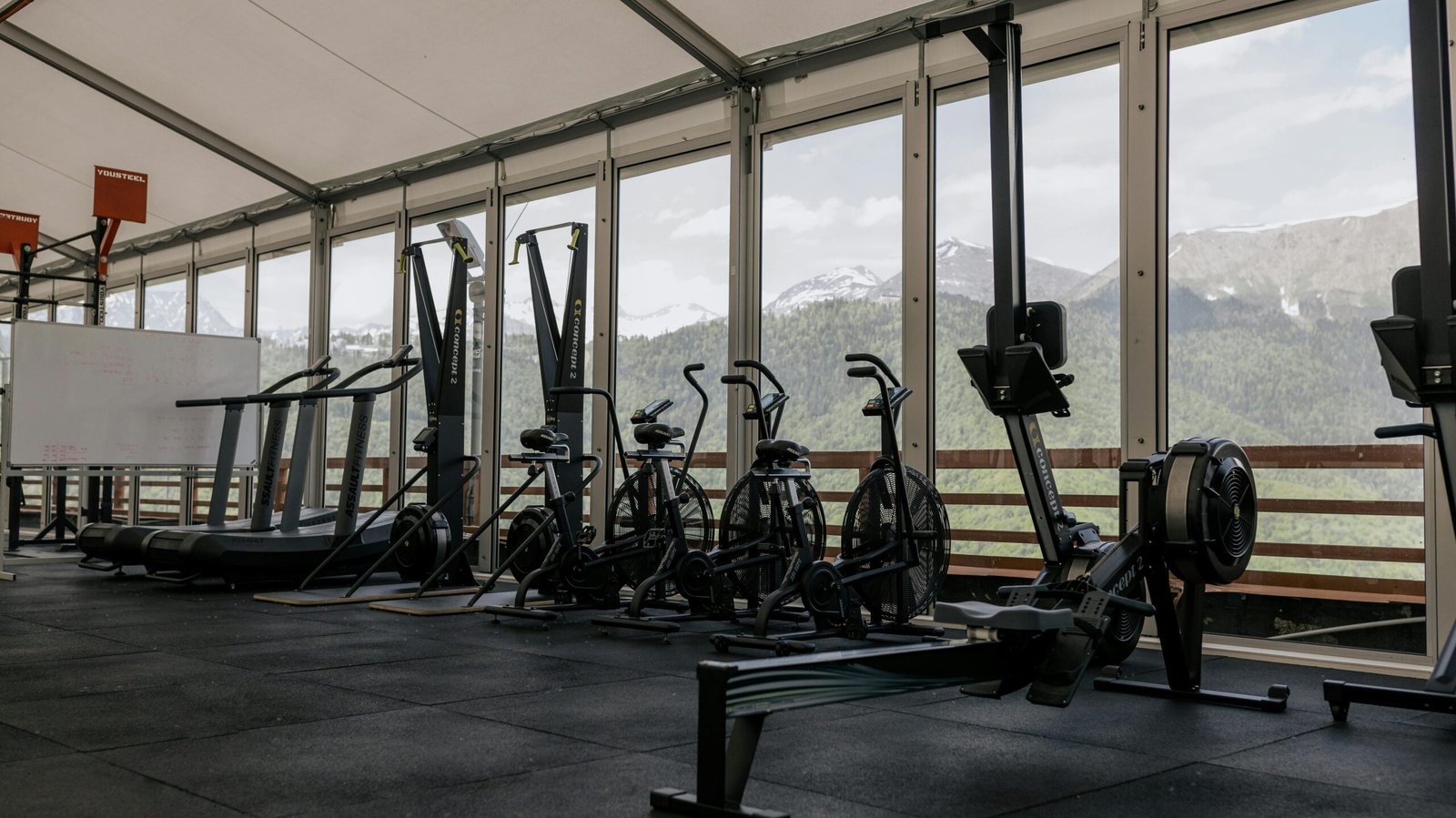 Spacious indoor gym featuring state-of-the-art equipment with scenic mountain views outside large windows.